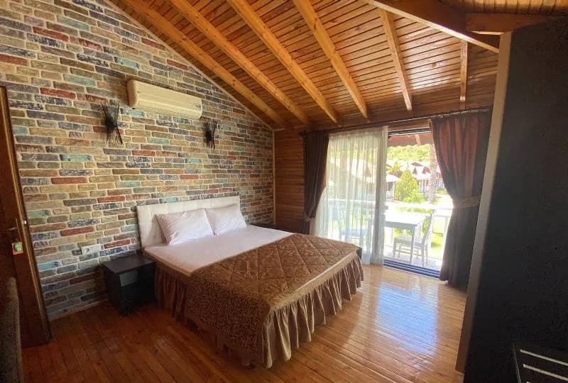 Club Sun Village Eko oda: çift kişilik yatak, taş duvar ve ahşap tavan