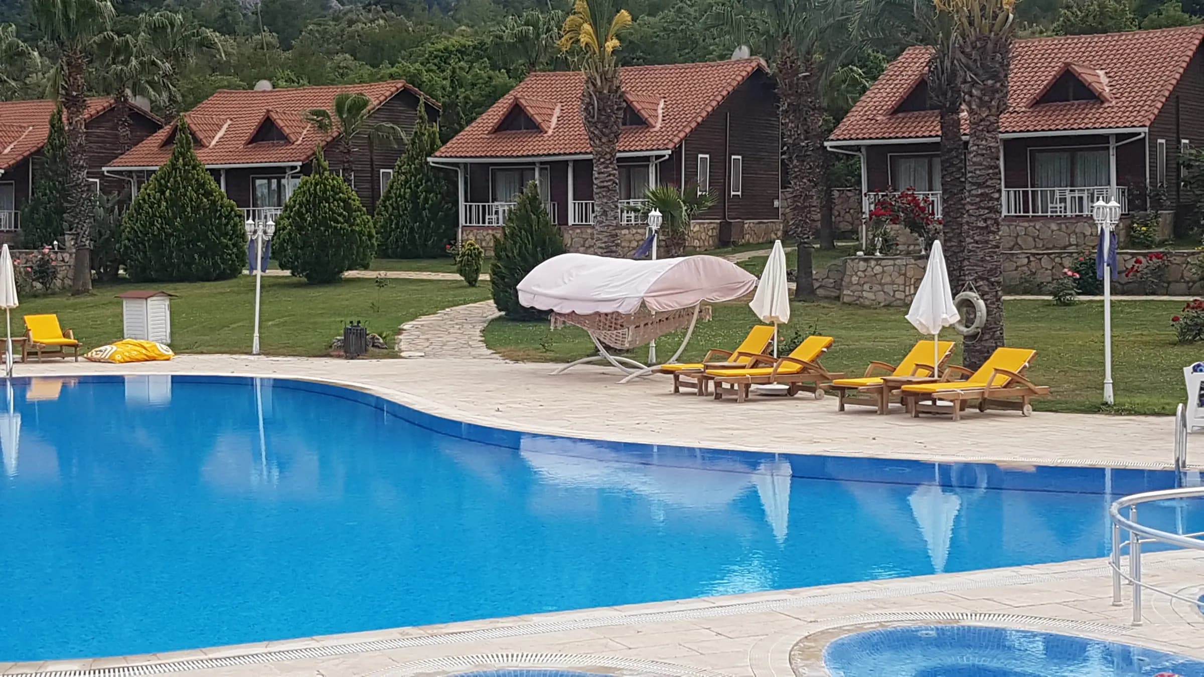 Club Sun Village havuz ve ahşap bungalovlar, şezlonglar ve hamak